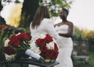 Wedding bouquets and two women exchanging vows.
